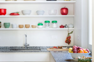 Kuchyňská linka s otevřenými policemi, žulovou deskou a sbírkou nádobí spojuje praktičnost s osobitou atmosférou domova.