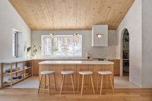 Detail kuchyňské linky s otevřenými policemi, keramickým nádobím a přirozeným světlem z okna