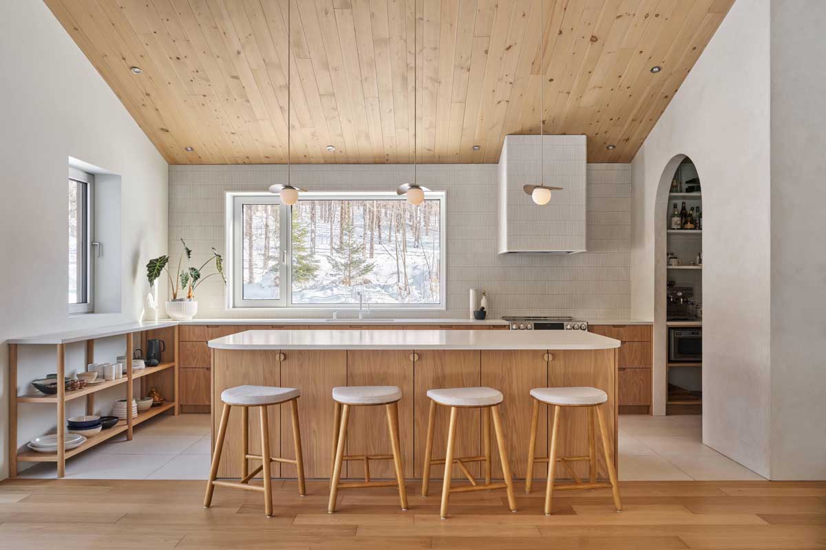 Detail kuchyňské linky s otevřenými policemi, keramickým nádobím a přirozeným světlem z okna