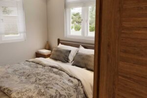 Útulná ložnice v tiny house s manželskou postelí a přírodními tóny dřeva.