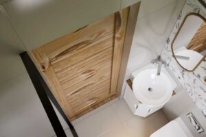 Koupelna v tiny house s umyvadlem a posuvnými dřevěnými dveřmi.