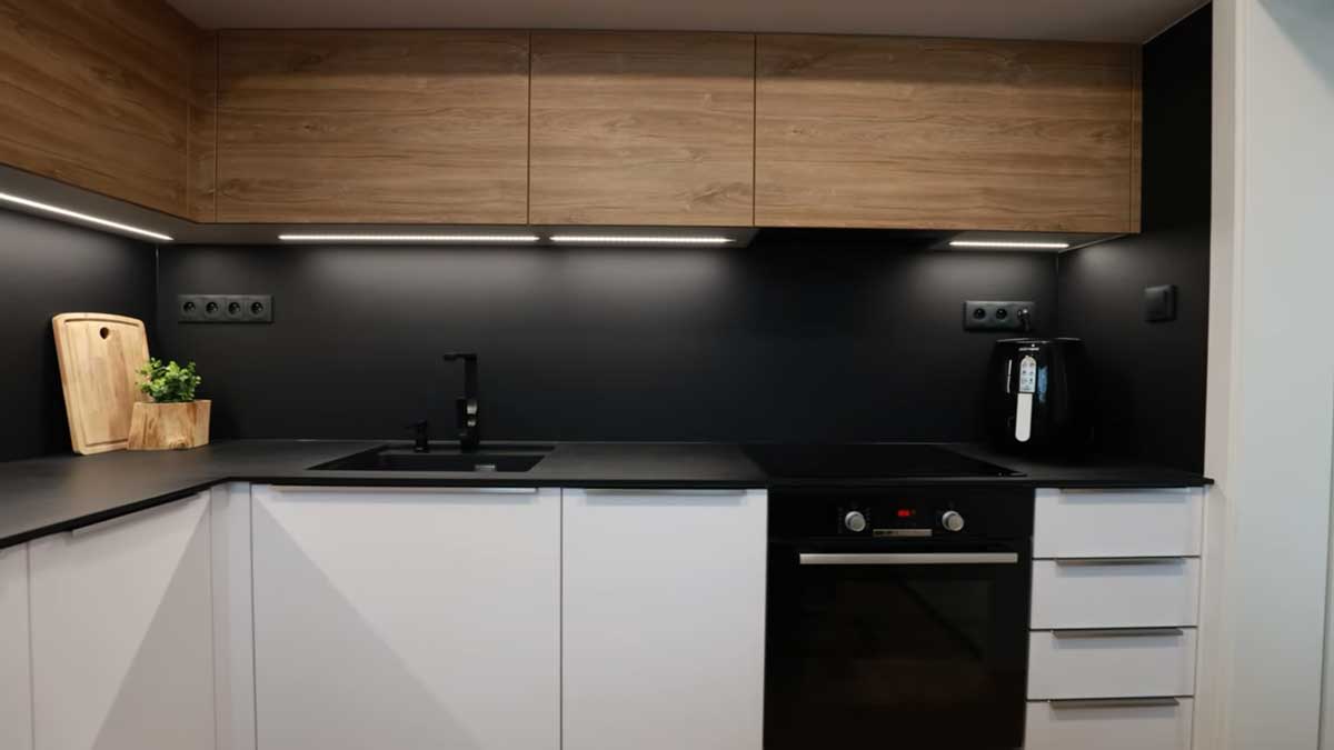 Nová kuchyňská linka v kombinaci bílé a dřeva s černou pracovní plochou vytváří čistý a funkční prostor.