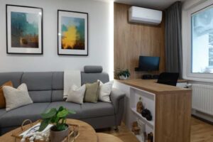 Obývací pokoj doplněný o pracovní zónu s dřevěným stolem přirozeně propojuje práci a relaxaci.