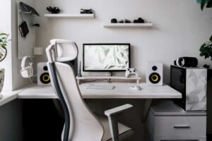 Minimalistický pracovní kout s počítačem a ergonomickou židlí nabízí čistý a funkční prostor pro soustředění i relax.