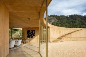 Pohled z interiéru přes prosklenou stěnu do kruhového nádvoří a okolní krajiny.