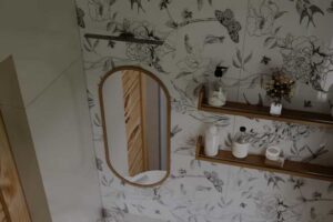 Detail koupelny s dekorativními policemi a květinovým obkladem.