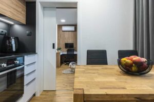 Moderní kuchyně s posuvnými dveřmi plynule navazuje na obytný prostor a propojuje jednotlivé části bytu.