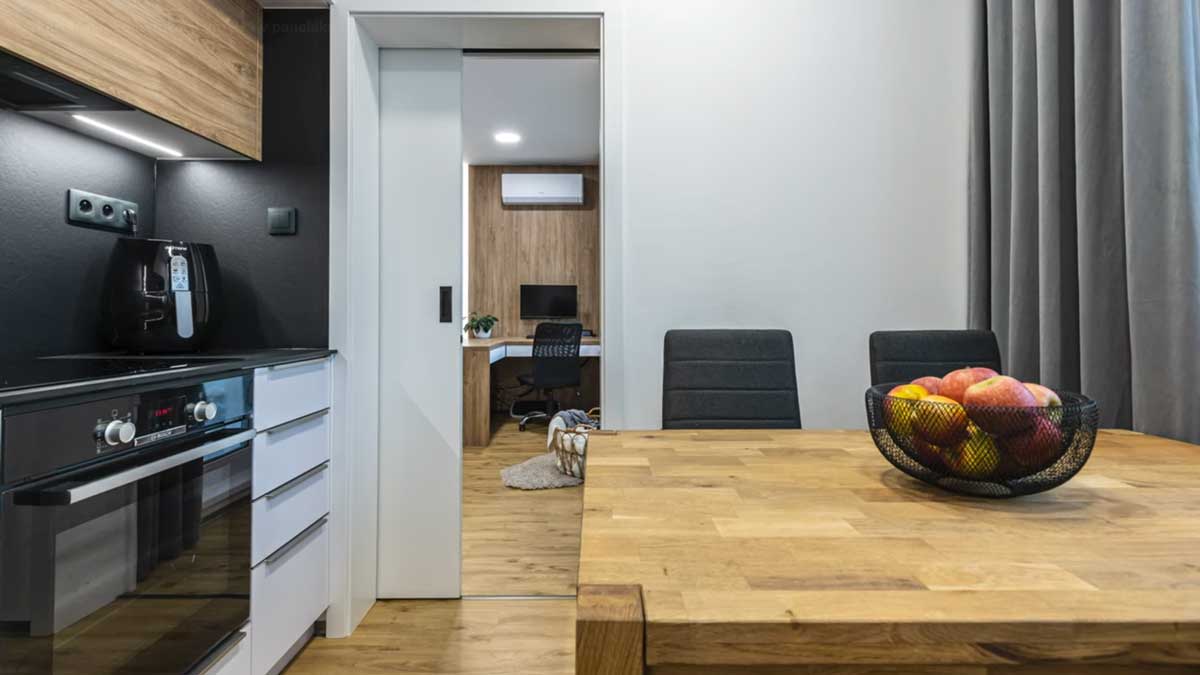 Moderní kuchyně s posuvnými dveřmi plynule navazuje na obytný prostor a propojuje jednotlivé části bytu.