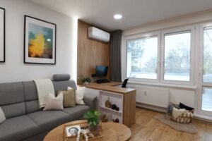 Obývací pokoj s pracovním koutem kombinuje pohodlnou sedačku s praktickým pracovním stolem a dostatkem denního světla.