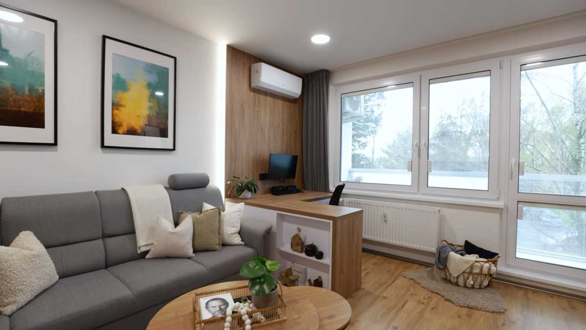 Obývací pokoj s pracovním koutem kombinuje pohodlnou sedačku s praktickým pracovním stolem a dostatkem denního světla.