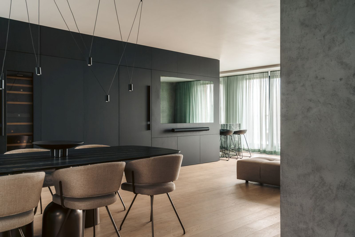Otevřený obytný prostor propojuje jídelnu, kuchyň i relaxační zónu, přičemž jednotná barevná paleta a materiály vytvářejí harmonický celek.