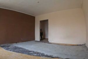 Vybouraný pokoj s odhalenou podlahou a stěnami ukazuje radikální začátek rekonstrukce panelákového bytu.