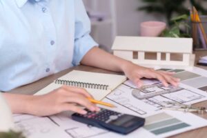 Žena plánuje rekonstrukci nad půdorysem bytu a počítá rozpočet s pomocí návrhů a barevných vzorků