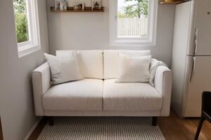 Malá světlá pohovka v obytné části tiny house vedle kuchyně.