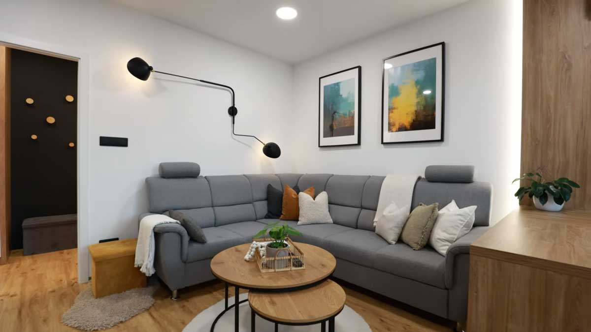 Rohová sedačka v neutrálních tónech doplněná dekorativními polštáři vytváří útulné místo pro odpočinek.