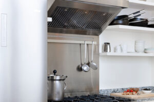 Profesionální nerezový sporák s dvojitou troubou a otevřenými policemi tvoří dominantní prvek malé florentské kuchyně.