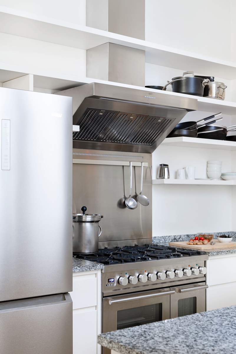 Profesionální nerezový sporák s dvojitou troubou a otevřenými policemi tvoří dominantní prvek malé florentské kuchyně.
