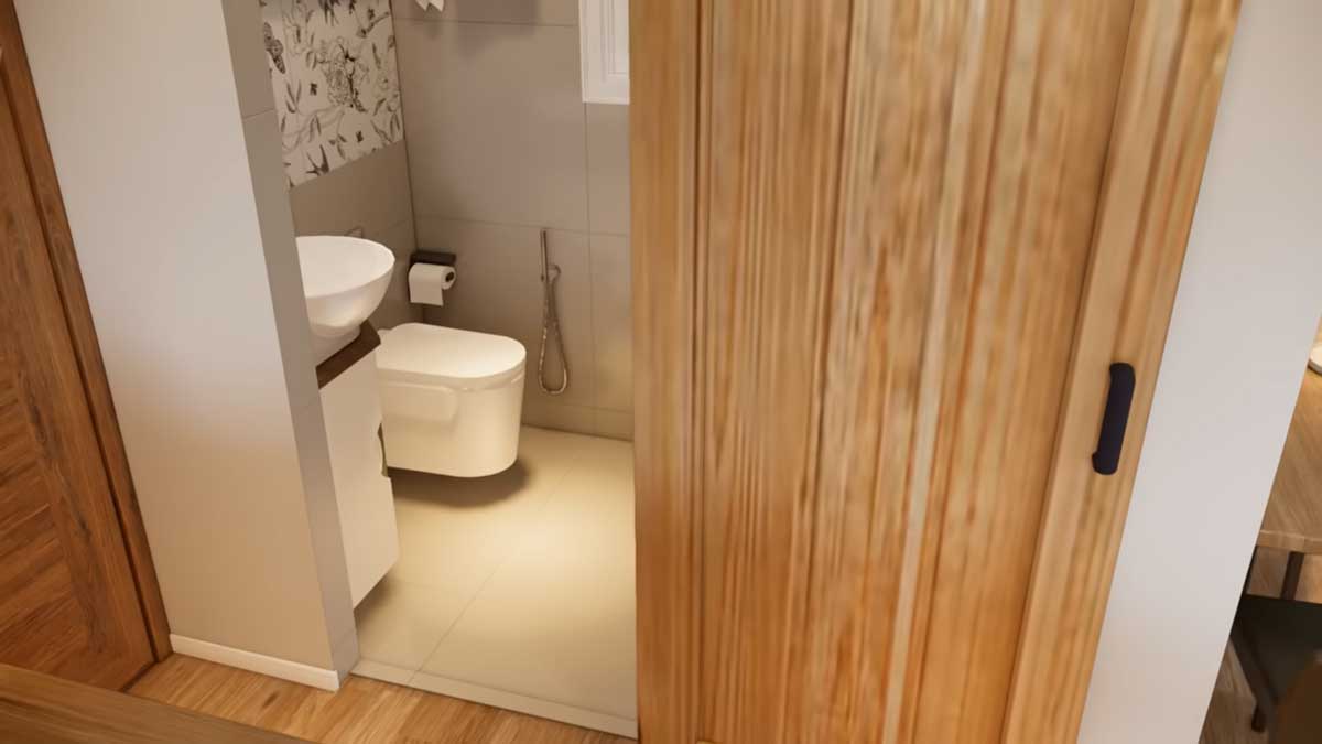 Koupelna v tiny house s toaletou, umyvadlem a posuvnými dřevěnými dveřmi.