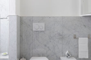 Koupelna obložená mramorem Carrara kombinuje toaletu, bidet a čisté linie v elegantně střídmém provedení.