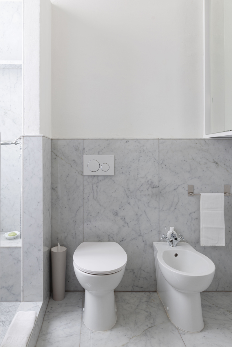 Koupelna obložená mramorem Carrara kombinuje toaletu, bidet a čisté linie v elegantně střídmém provedení.