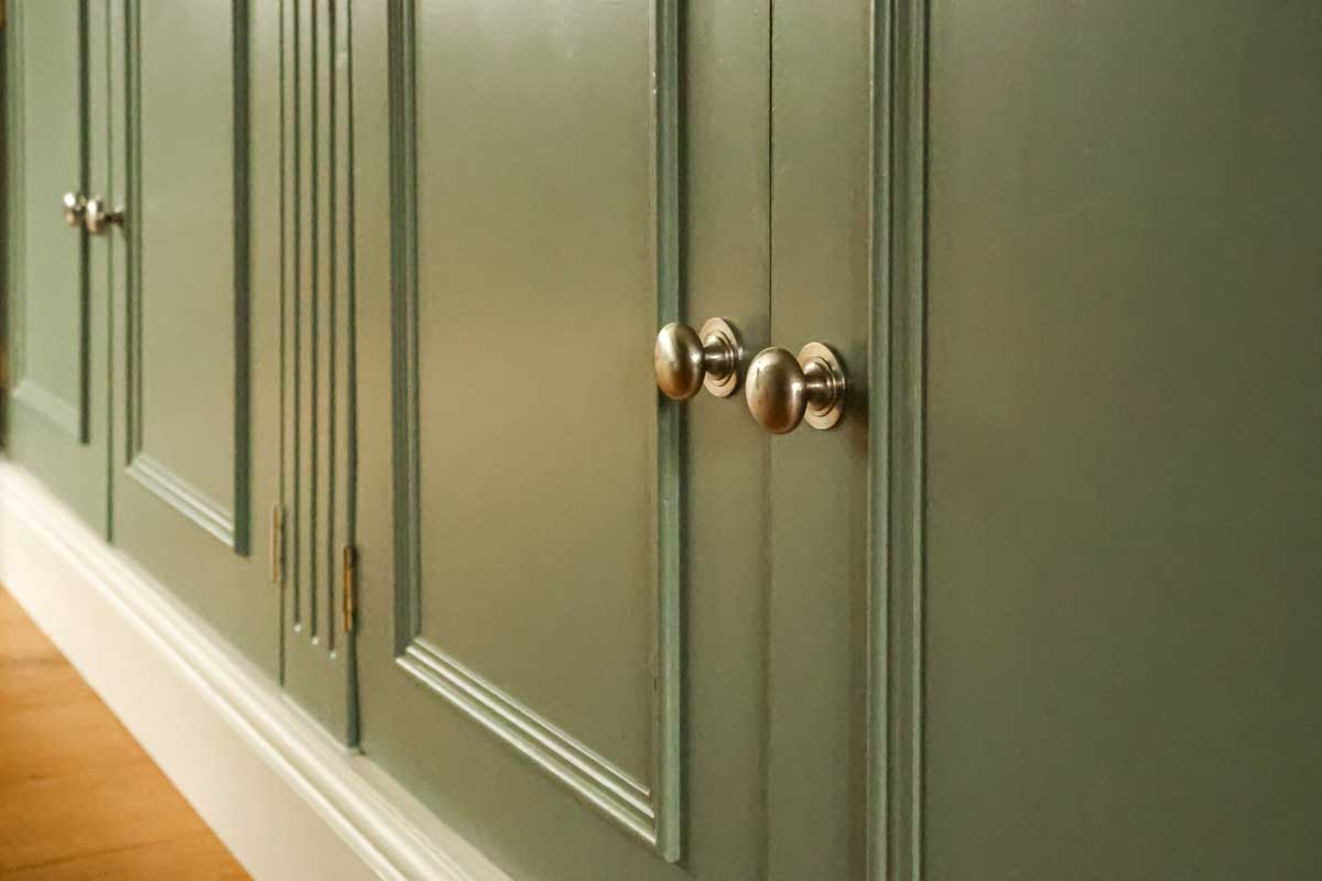 Detail nábytkových dvířek s kovovými úchytkami ukazuje jak drobné detaily ovlivňují celkový dojem z interiéru