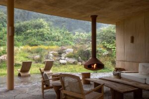 Kryté venkovní posezení s krbem a výhledem do zelené krajiny.