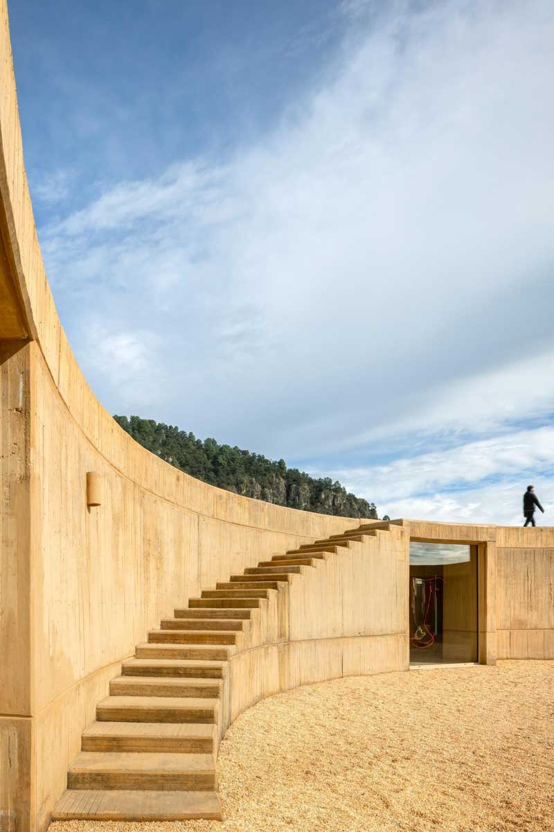 Betonové schodiště vedoucí po obloukové stěně domu směrem na střechu.