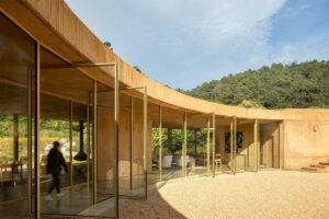 Otevřené prosklené stěny domu umožňující přirozené proudění vzduchu a propojení s exteriérem.