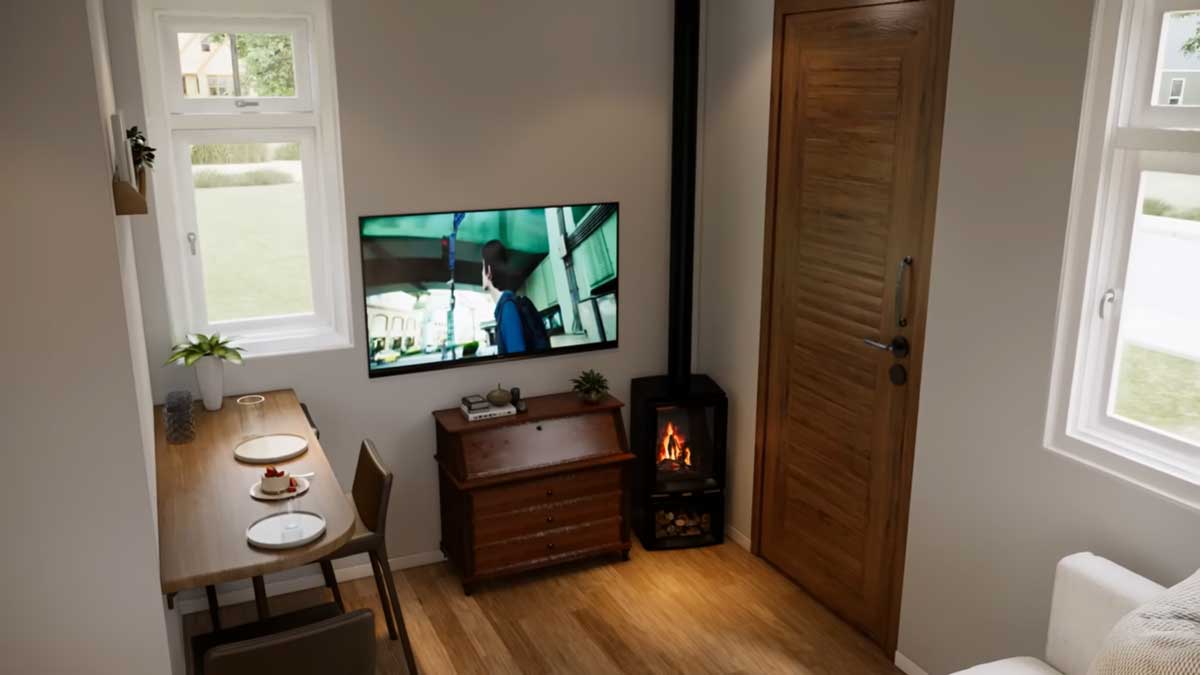 Obytná část tiny house s jídelním stolem, televizí a krbovými kamny u vstupu.