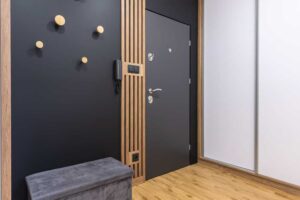 Vstupní prostor s černou stěnou dřevěnými lamelami a vestavěnými skříněmi působí elegantně a organizovaně.