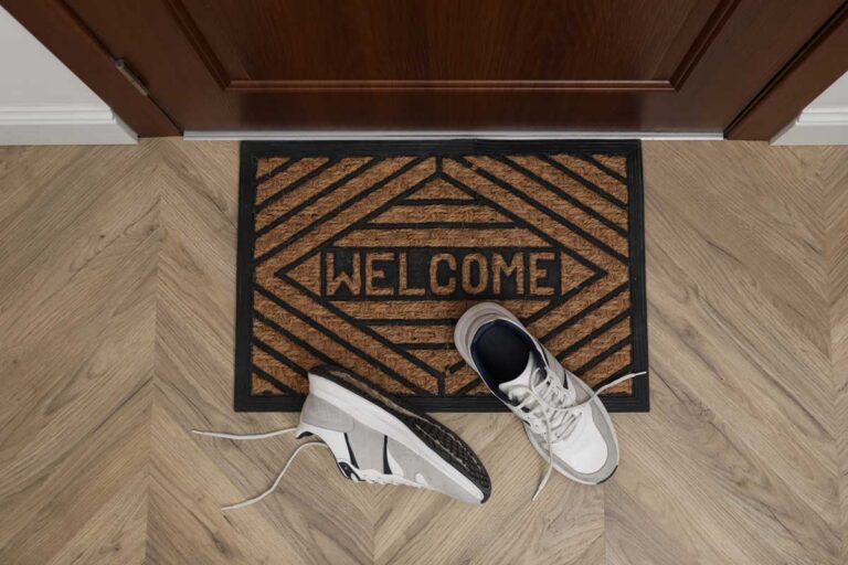 Vstupní rohožka a boty u dveří ukazují první moment kontaktu s interiérem domova.