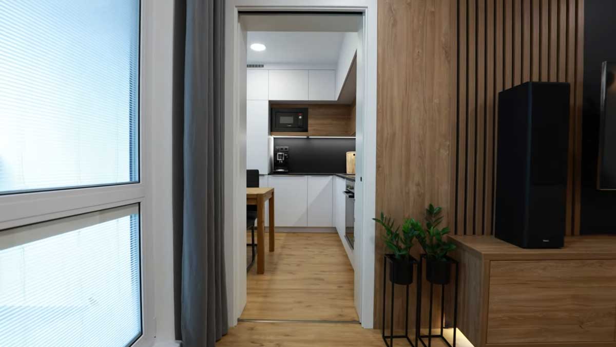 Pohled z obývacího prostoru do kuchyně ukazuje propojení místností a jednotný design celého bytu.