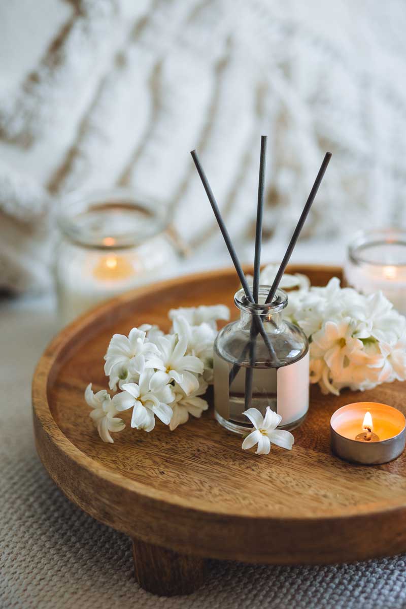 Stylový interiérový difuzér se svíčkami a květinami vytváří příjemnou vůni a útulnou atmosféru domova.