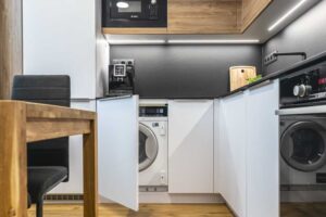 Pračka nenápadně ukrytá v kuchyňské lince zachovává čistý vzhled prostoru a nenarušuje design interiéru.