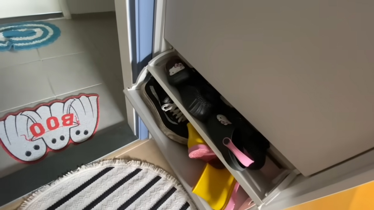 Výklopný botník u vstupu pomáhá udržet pořádek v úzké předsíni malého bytu.