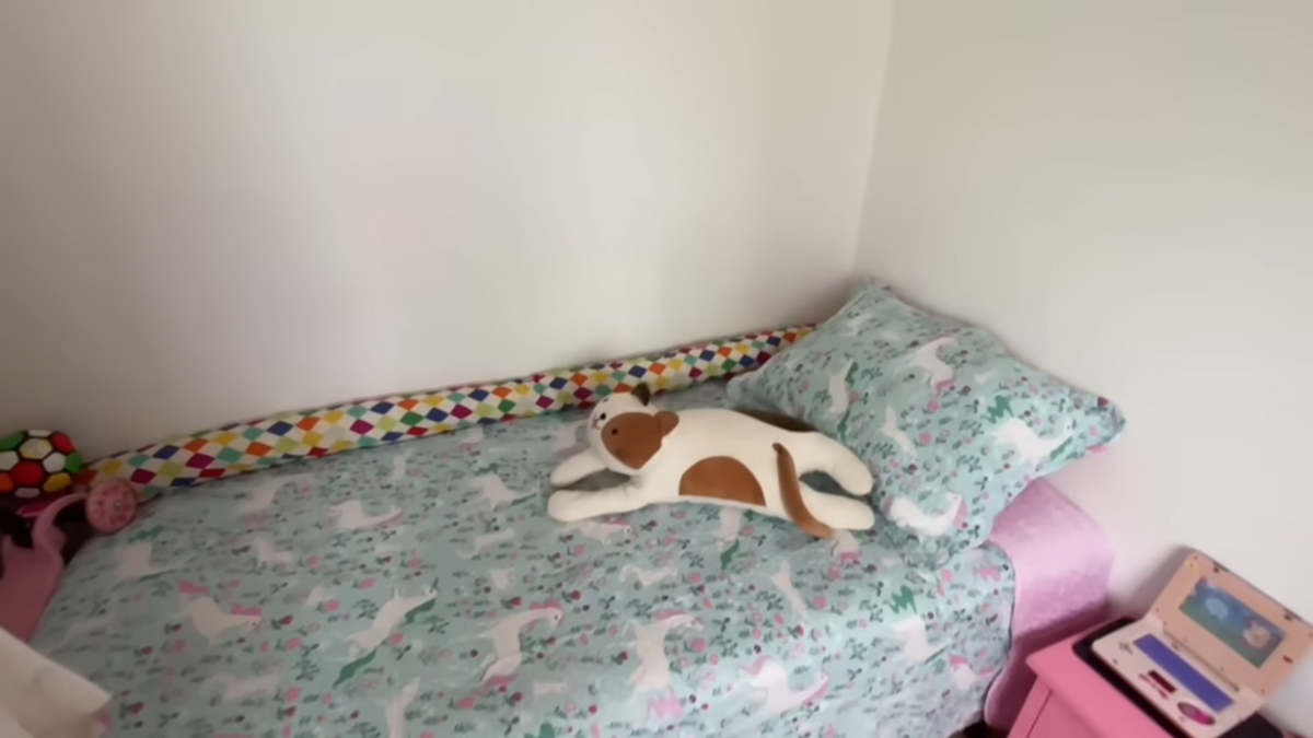 Jednolůžková postel s pastelovým povlečením vytváří v malém pokoji klidné místo na spaní i odpočinek.