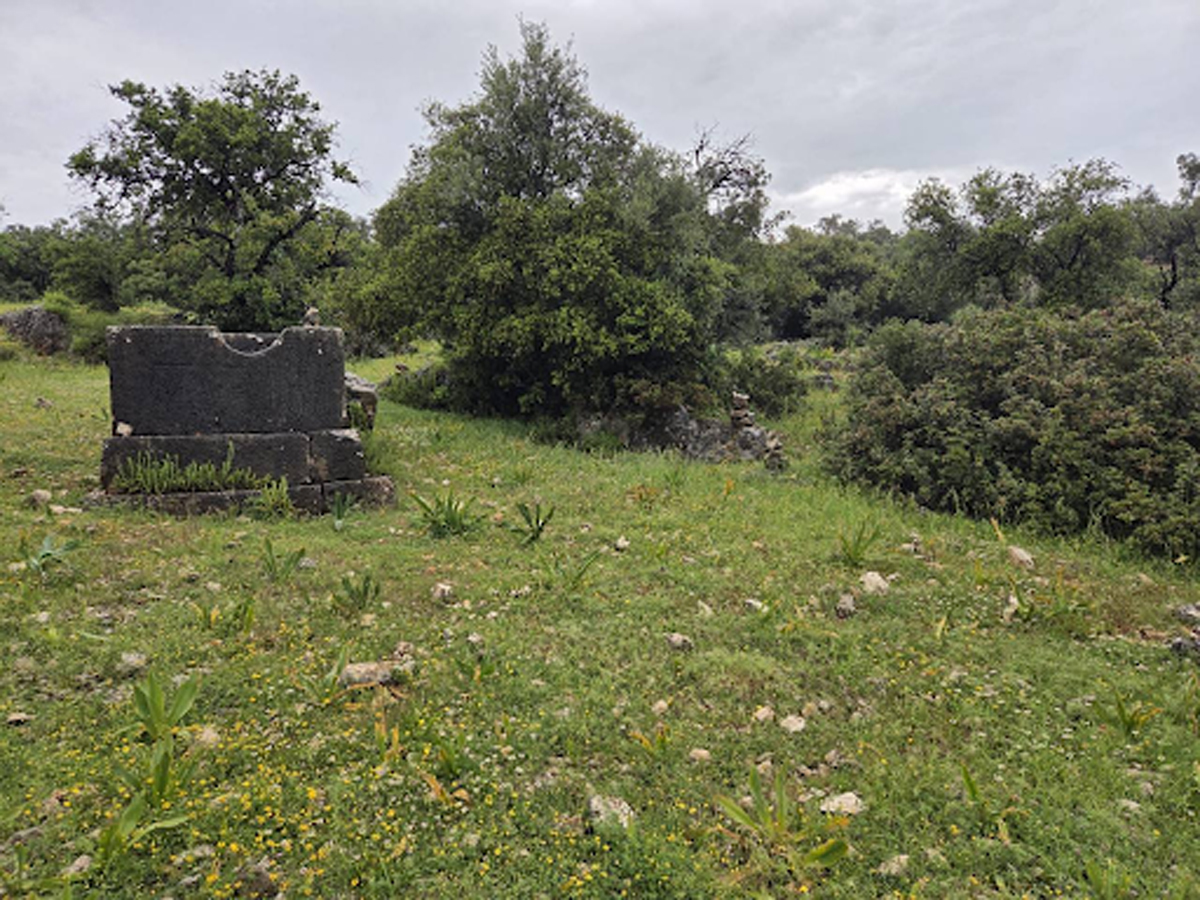 Pozůstatky starověkých staveb a kamenných ruin v zelené krajině podél Lýkijské stezky.