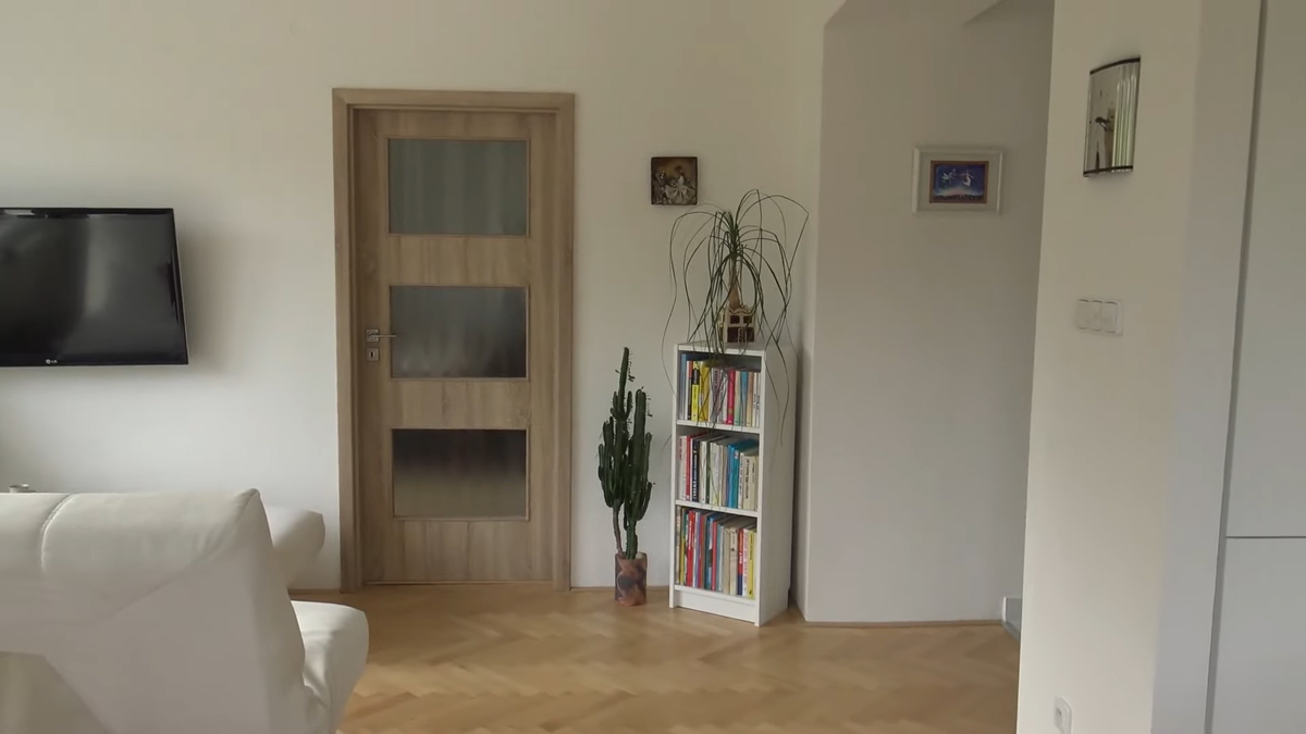 Minimalistická knihovna a vstup do ložnice ukazují snahu o jednoduchost, která kontrastuje s jinými částmi interiéru.