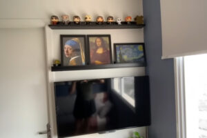 Televizní stěnu doplňují černé police s obrazy a dekoracemi inspirovanými moderním uměním.