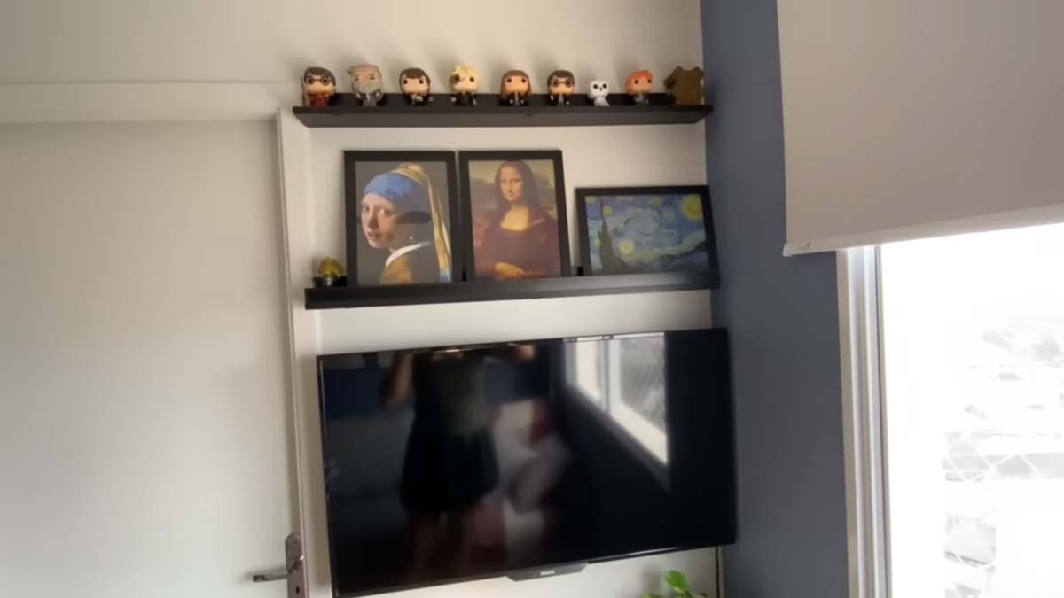 Televizní stěnu doplňují černé police s obrazy a dekoracemi inspirovanými moderním uměním.