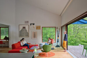 Hlavní obytný prostor domu Riverhouse propojuje minimalistický interiér s přírodou díky velkým posuvným oknům a otevřenému výhledu do zeleně.