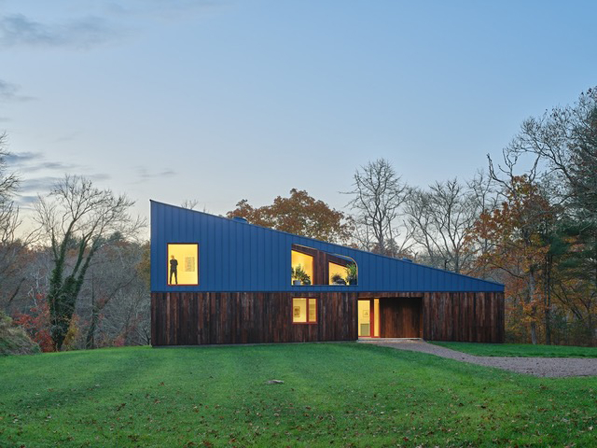 Moderní dům Riverhouse zaujme kombinací tmavého dřeva, modré střechy a netradiční siluety zasazené do přírodního prostředí.