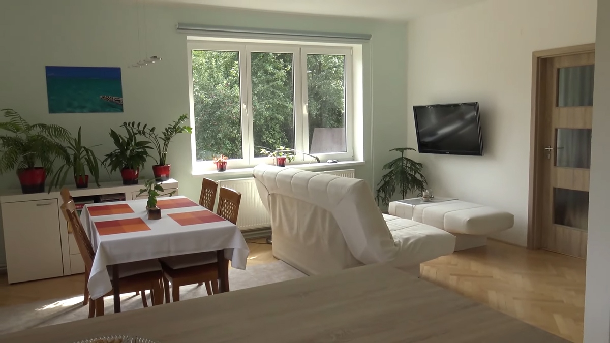 Otevřená denní zóna s kuchyní, jídelním koutem a obývacím prostorem ukazuje modernizovaný byt s důrazem na světlo a propojení místností.