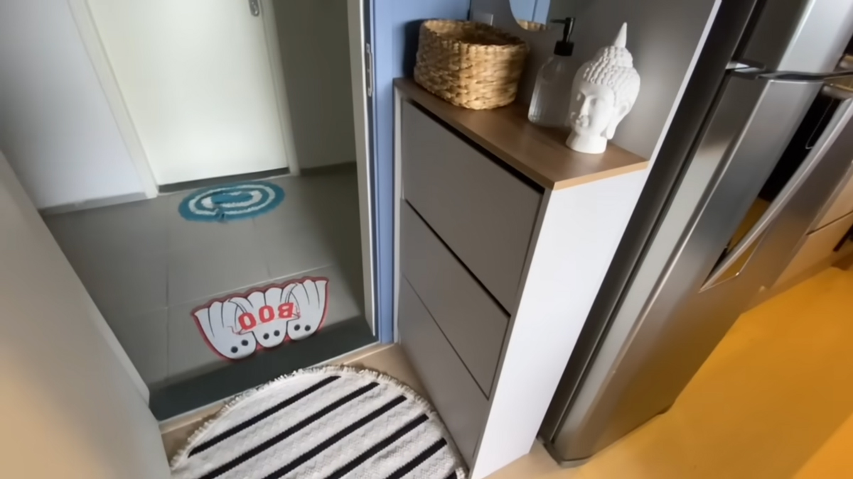 Úzká vstupní část bytu kombinuje botník, dekorace a praktické úložné řešení v minimalistickém stylu.