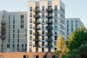 Štíhlá obytná věž s jasně členěnou fasádou, vertikálními výřezy pro balkony a střešní zahradou dodává panoramatu města výrazný akcent.