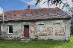 Fasáda domu před rekonstrukcí byla poškozená vlhkostí, opadávající omítkou a dlouhodobým zanedbáním.