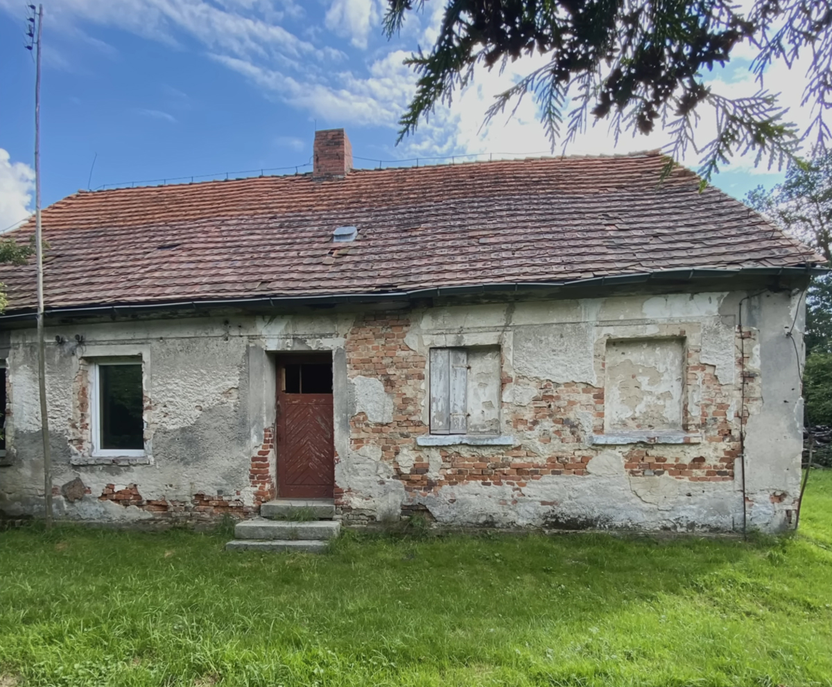 Fasáda domu před rekonstrukcí byla poškozená vlhkostí, opadávající omítkou a dlouhodobým zanedbáním.