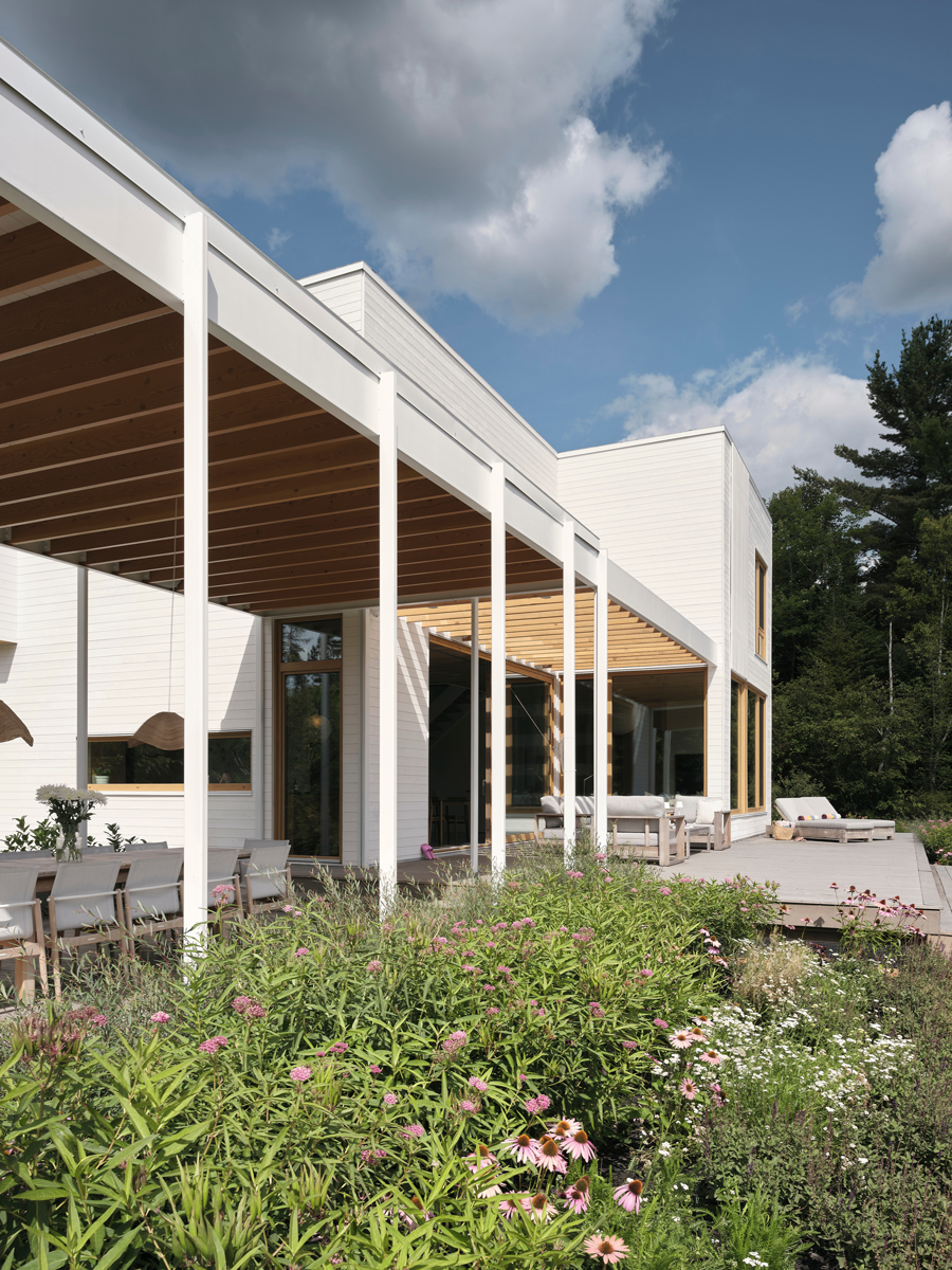 Pergola s odhalenou dřevěnou konstrukcí propojuje terasu, zahradu a hlavní obytné místnosti domu.