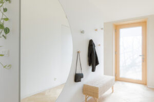 Minimalistická předsíň s velkoformátovým zrcadlem a světlou dubovou podlahou působí vzdušně a elegantně.