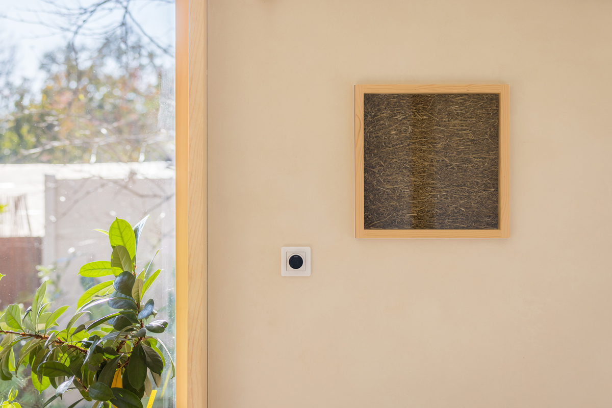 Detail interiérové stěny s přírodním materiálem odkazuje na důraz domu na jednoduchost a udržitelné řešení.